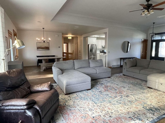 living room with crown molding, ceiling fan with notable chandelier, and wood-type flooring