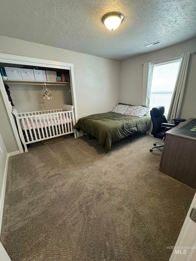 bedroom with visible vents, a textured ceiling, and carpet