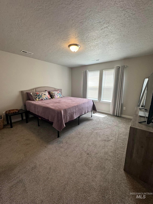 bedroom featuring visible vents, carpet floors, and a textured ceiling