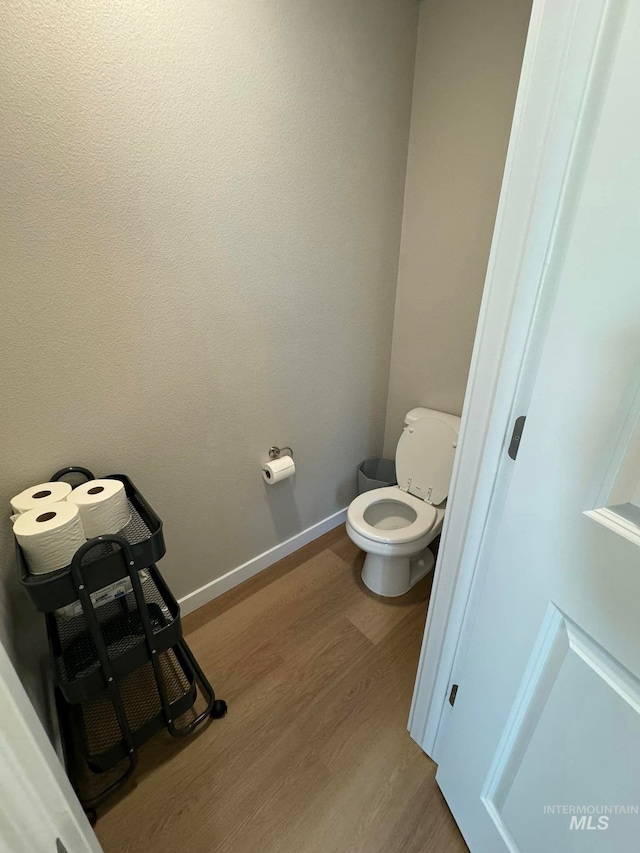 bathroom featuring toilet, wood finished floors, and baseboards