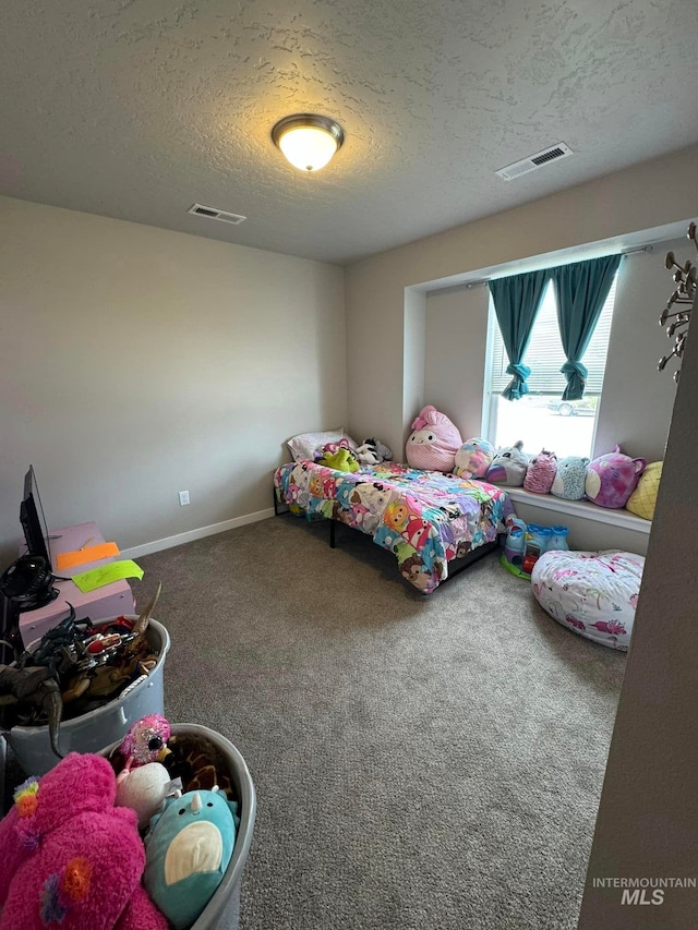 carpeted bedroom with baseboards, visible vents, and a textured ceiling