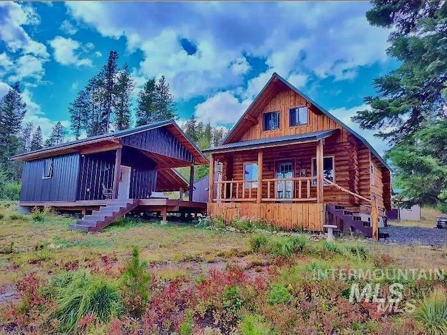 rear view of property with board and batten siding, covered porch, stairs, and log siding