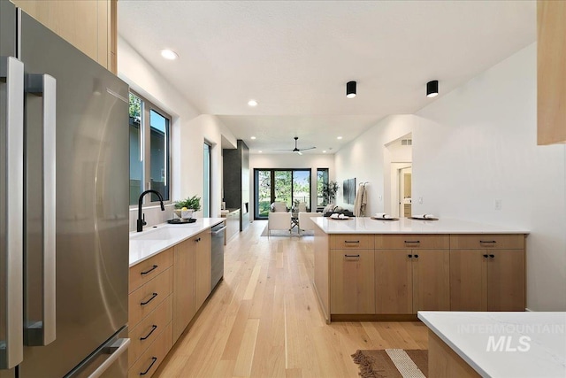 kitchen with light brown cabinets, sink, light hardwood / wood-style flooring, ceiling fan, and stainless steel appliances