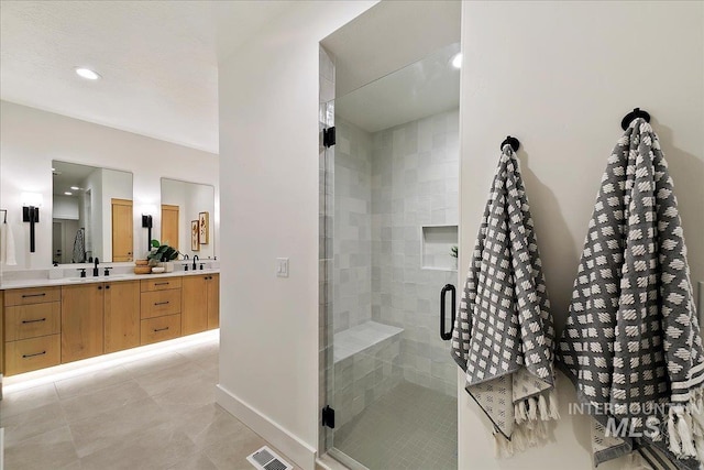 bathroom featuring a shower with door, vanity, and tile patterned flooring