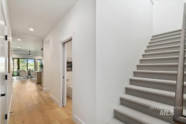 staircase with wood-type flooring and ceiling fan