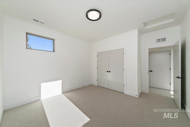 unfurnished bedroom featuring light colored carpet and a closet