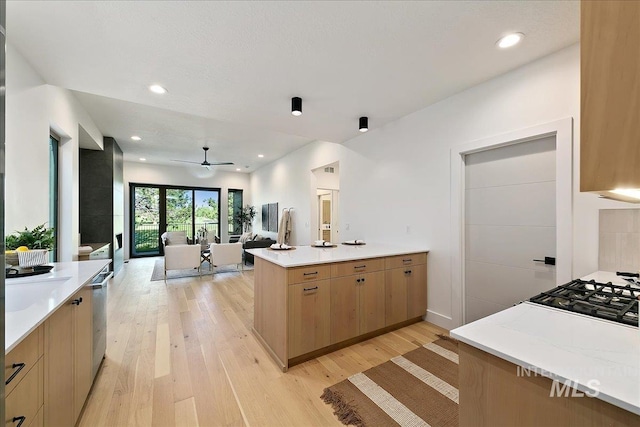 kitchen with ceiling fan, gas stovetop, light brown cabinetry, light hardwood / wood-style floors, and kitchen peninsula