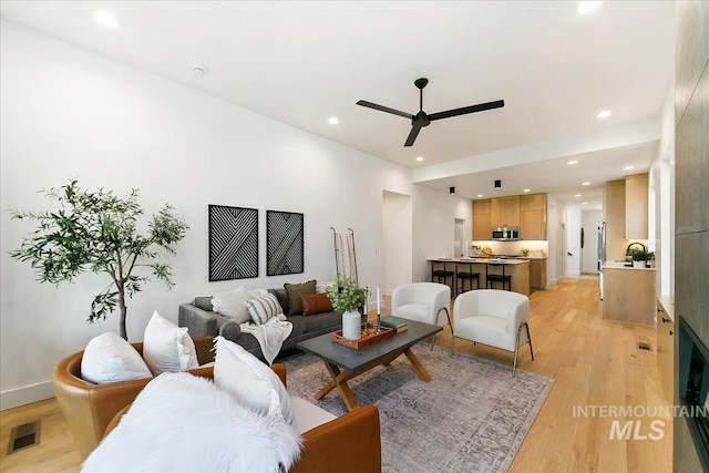 living room featuring light hardwood / wood-style floors and ceiling fan