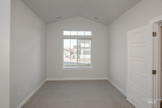 spare room featuring lofted ceiling, visible vents, and light colored carpet