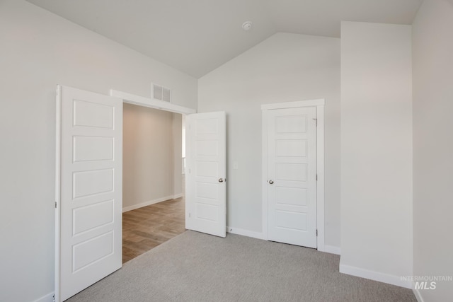 unfurnished bedroom with lofted ceiling, baseboards, visible vents, and carpet floors