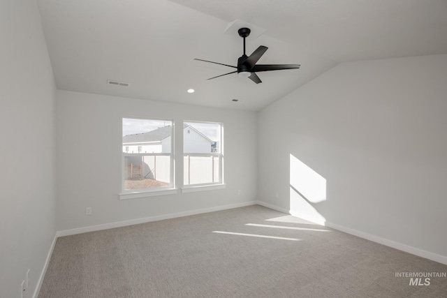 empty room featuring carpet, vaulted ceiling, visible vents, baseboards, and ceiling fan