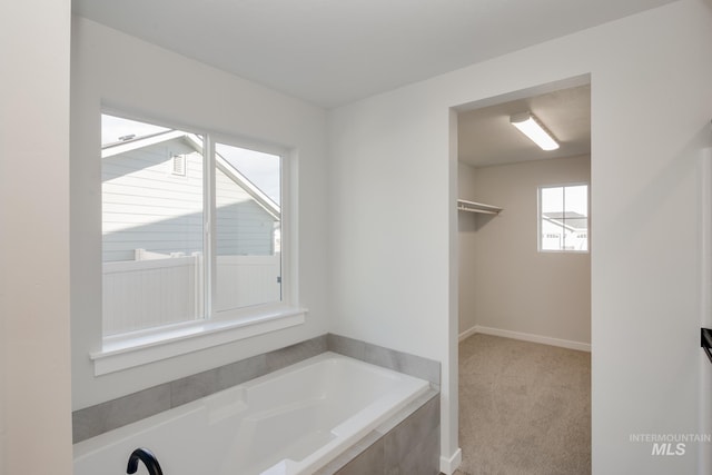 bathroom featuring a garden tub and baseboards