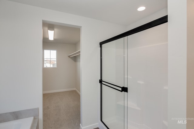 bathroom featuring recessed lighting, a bath, baseboards, and a stall shower