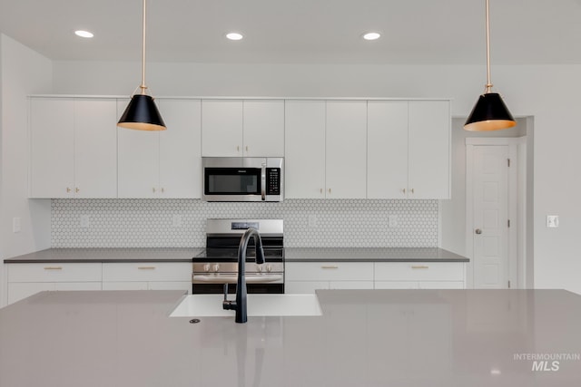 kitchen featuring decorative backsplash, decorative light fixtures, white cabinetry, and appliances with stainless steel finishes