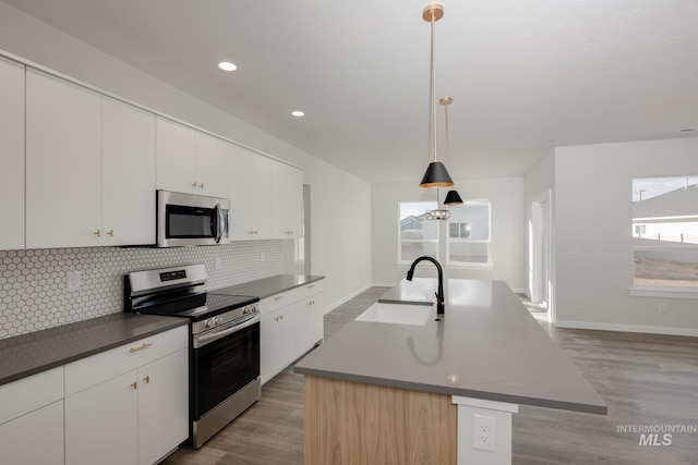 kitchen with backsplash, dark countertops, stainless steel appliances, and a sink