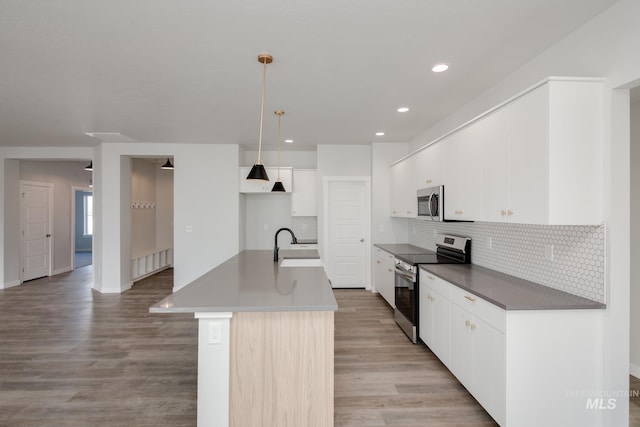 kitchen with backsplash, stainless steel appliances, light wood-type flooring, and a sink