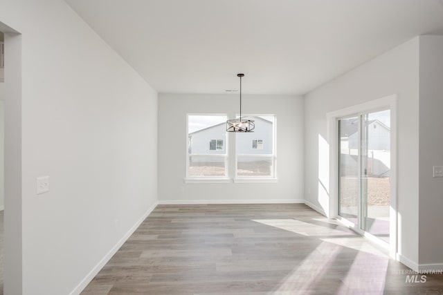 unfurnished dining area featuring baseboards, a notable chandelier, and a healthy amount of sunlight