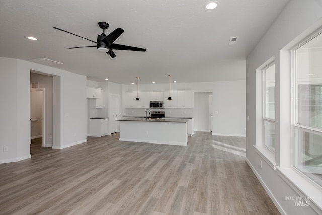 unfurnished living room featuring recessed lighting, a ceiling fan, a sink, light wood-style floors, and baseboards