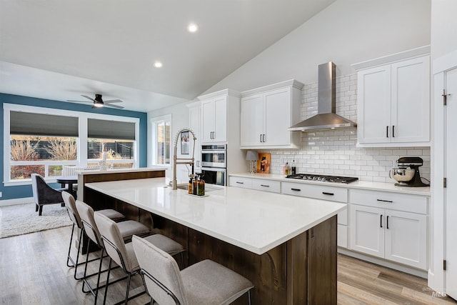 20513 N Glenisla Ave, Boise, ID 83714 - kitchen with lofted ceiling, white cabinetry, wall chimney range hood, and appliances with stainless steel finishes