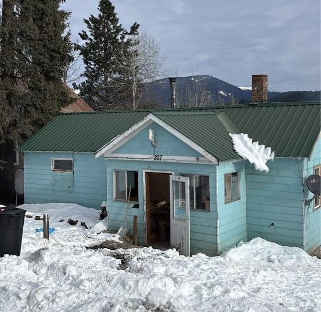 snow covered back of property featuring a mountain view