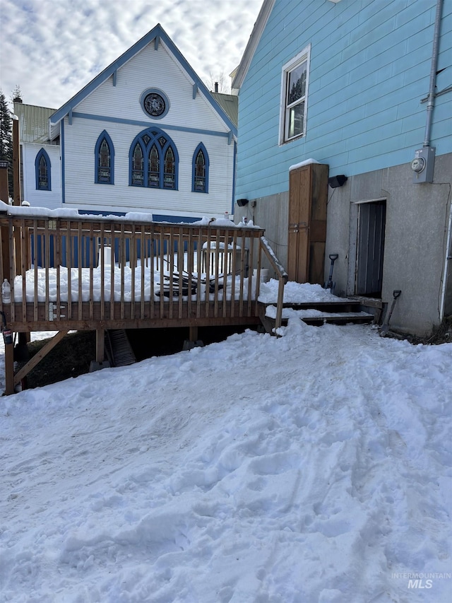 snow covered rear of property with a wooden deck