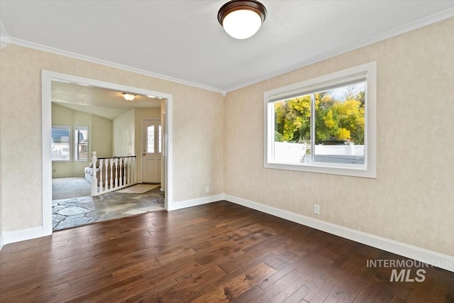 empty room featuring dark hardwood / wood-style flooring, ornamental molding, and plenty of natural light