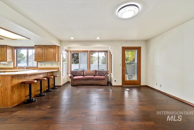 unfurnished living room with dark hardwood / wood-style flooring, sink, and a textured ceiling