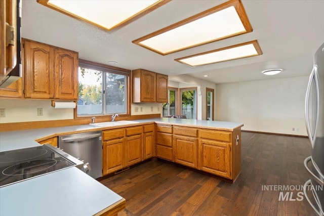 kitchen featuring dark wood-type flooring, kitchen peninsula, sink, and stainless steel appliances