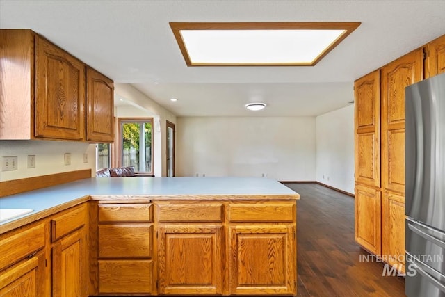 kitchen featuring kitchen peninsula, stainless steel refrigerator, and dark hardwood / wood-style floors