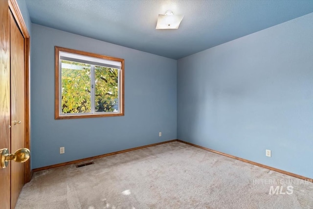 spare room featuring a textured ceiling and light carpet