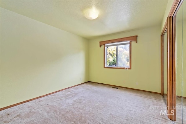 unfurnished bedroom with a textured ceiling, carpet flooring, and a closet