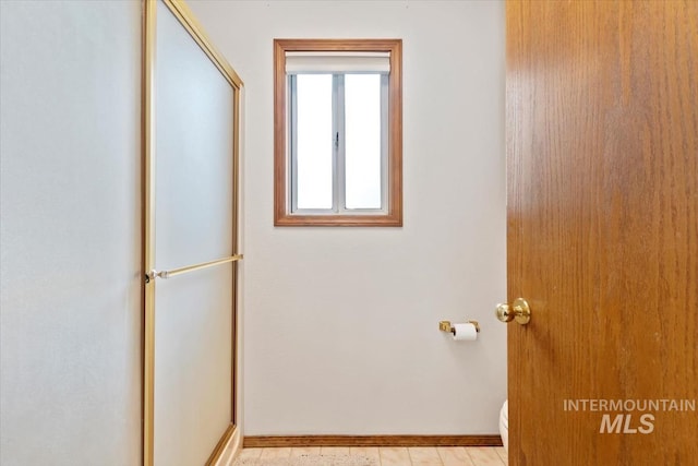 bathroom featuring toilet and a shower with door