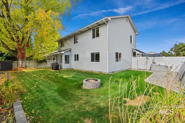 rear view of property featuring a yard and an outdoor fire pit