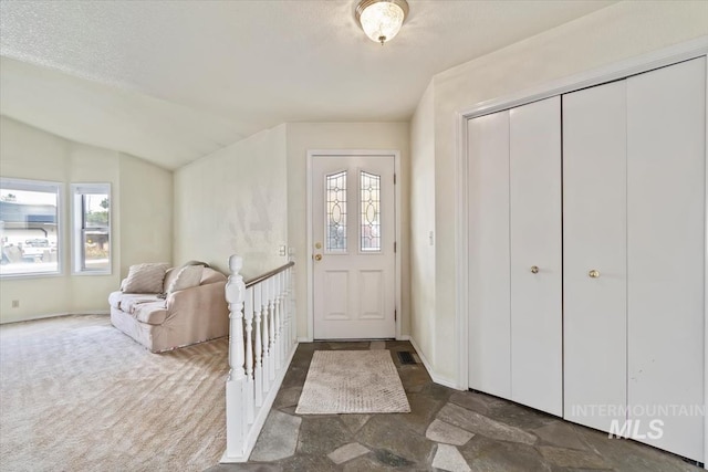 carpeted foyer entrance featuring vaulted ceiling and a textured ceiling