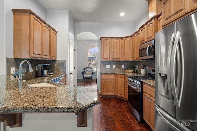 1814 E Grand Canyon Dr, Meridian, ID 83646 - kitchen with dark stone counters, stainless steel appliances, arched walkways, and a sink