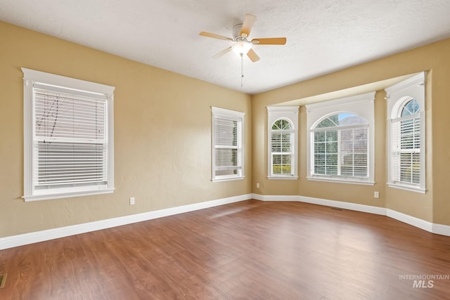 unfurnished room with ceiling fan, wood-type flooring, and a textured ceiling