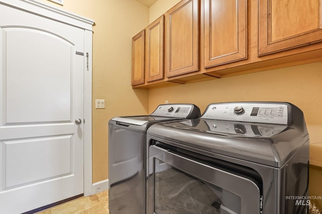 clothes washing area featuring independent washer and dryer and cabinets