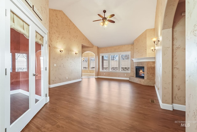 unfurnished living room with ceiling fan, a high end fireplace, dark wood-type flooring, and high vaulted ceiling