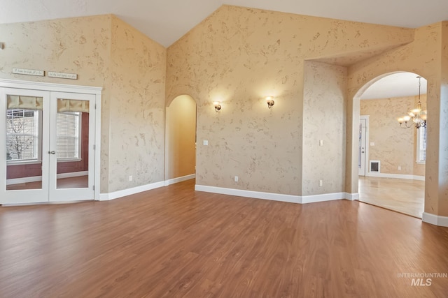 spare room featuring high vaulted ceiling, french doors, a notable chandelier, and hardwood / wood-style flooring