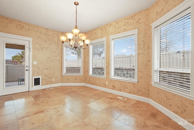 unfurnished dining area featuring a chandelier and a textured ceiling