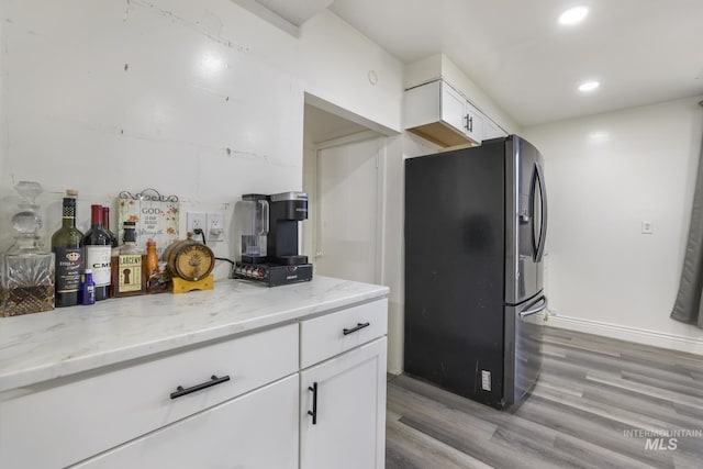 317 W C, Shoshone, ID 83352 - kitchen with light stone counters, white cabinetry, recessed lighting, light wood-type flooring, and stainless steel refrigerator with ice dispenser