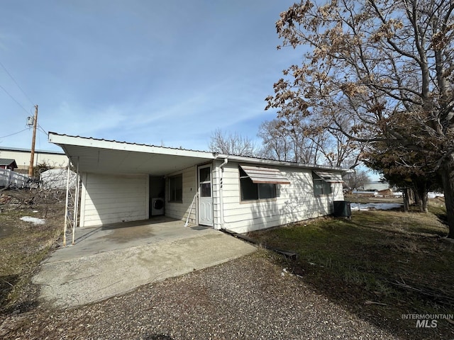 back of property featuring driveway, metal roof, central air condition unit, and an attached carport