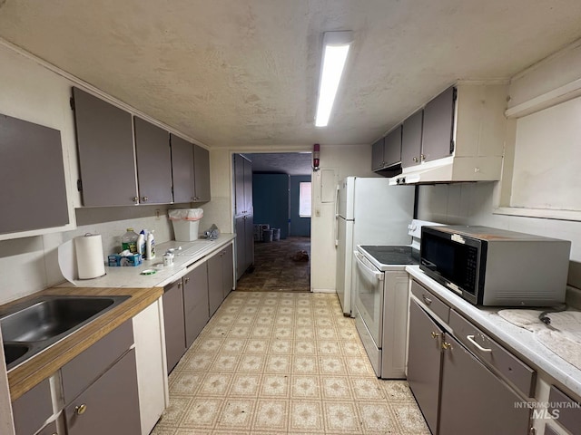 kitchen featuring white electric stove, stainless steel microwave, light countertops, light floors, and a sink