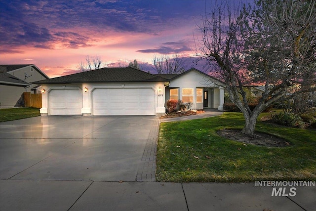 ranch-style home featuring a garage and a yard