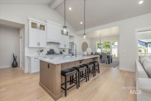11304 W Helenium Dr, Star, ID 83669 - kitchen with beamed ceiling, light wood-type flooring, a kitchen breakfast bar, decorative backsplash, and white cabinetry