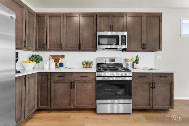 kitchen with stainless steel appliances, light wood finished floors, and light countertops