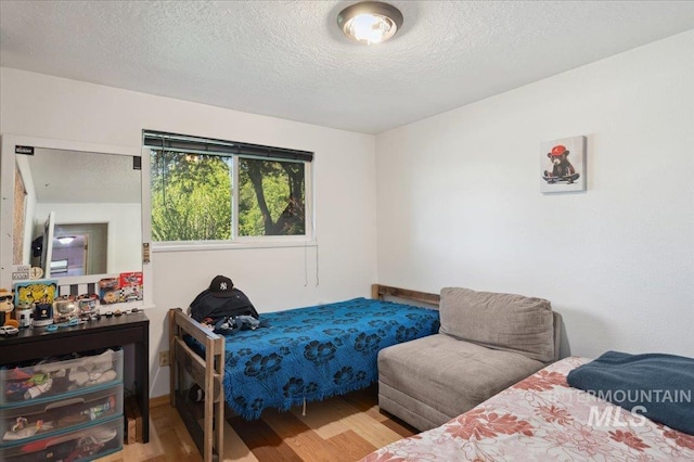 bedroom featuring wood finished floors, a textured ceiling, and baseboards