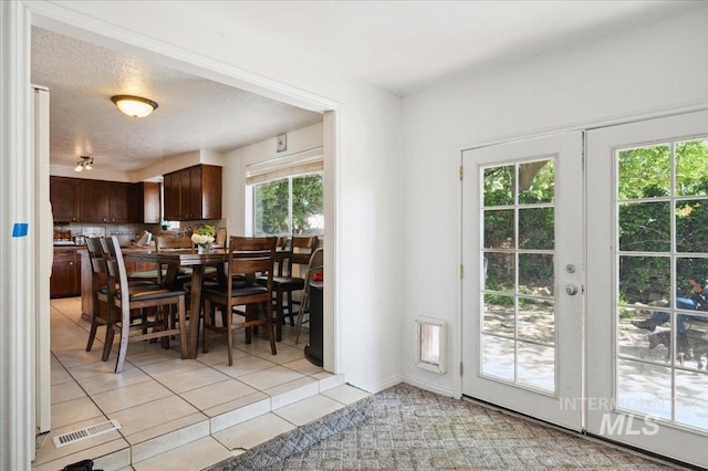 dining room featuring light tile patterned floors, a textured ceiling, and french doors