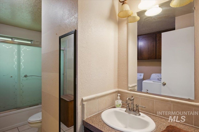 bathroom featuring toilet, shower / bath combination with glass door, washer and dryer, tile patterned flooring, and vanity