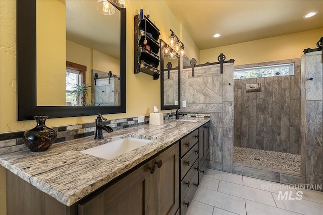 bathroom with tile patterned flooring, vanity, and a tile shower